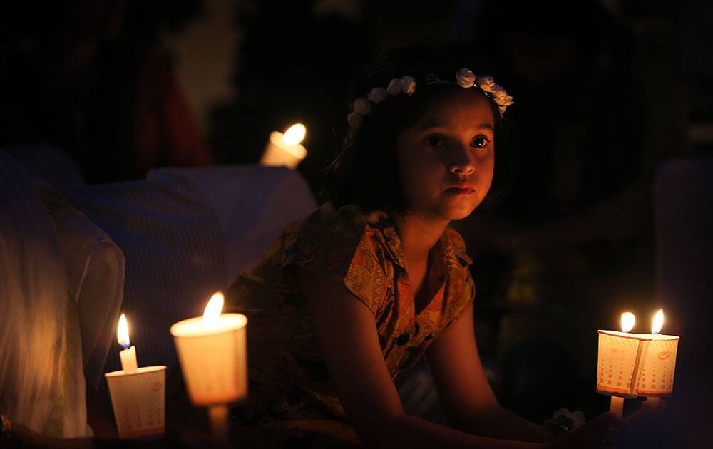 An Indian girl holds a candle during an awareness campaign by Greenpeace activists to save Mahan forest in the Indian state of Madhya Pradesh, on Earth Day in New Delhi.