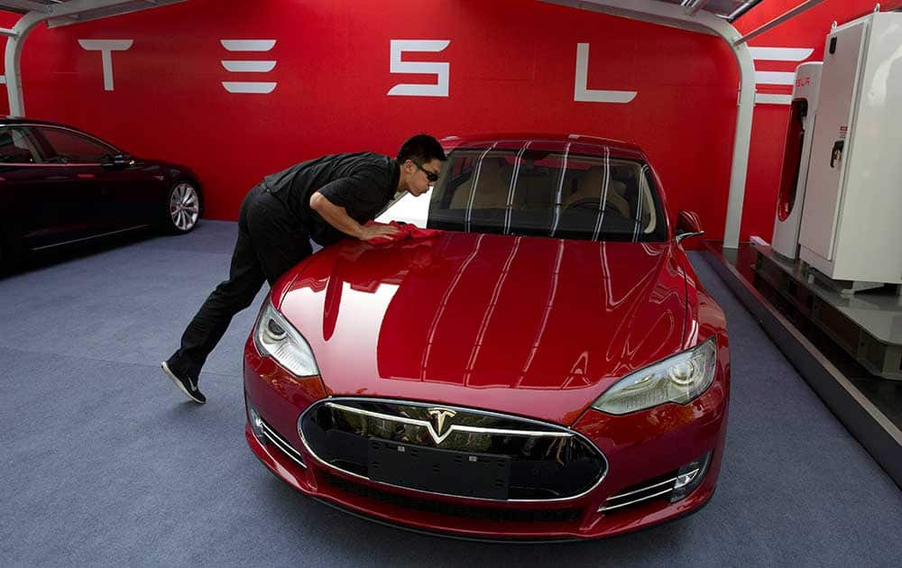 A worker cleans a Tesla Model S sedan before a event to deliver the first set of cars to customers in Beijing, China.