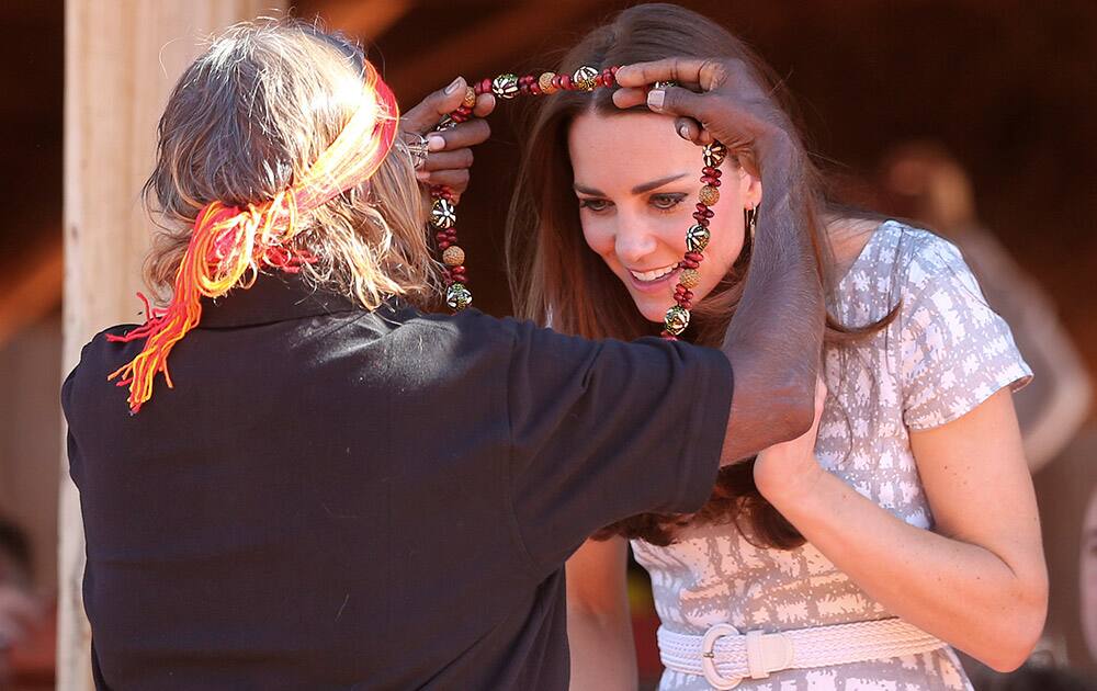 Britain`s Kate, the Duchess of Cambridge, receives a necklace from a local aboriginal woman at the Uluru Cultural center at Uluru, Australia.