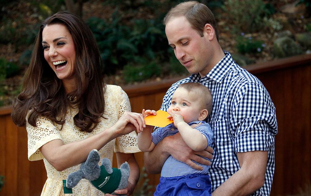 Britain`s Kate, the Duchess of Cambridge, and her husband Prince William react as their son Prince George bites a small present that was given to him during a visit to Sydney`s Taronga Zoo, Australia.