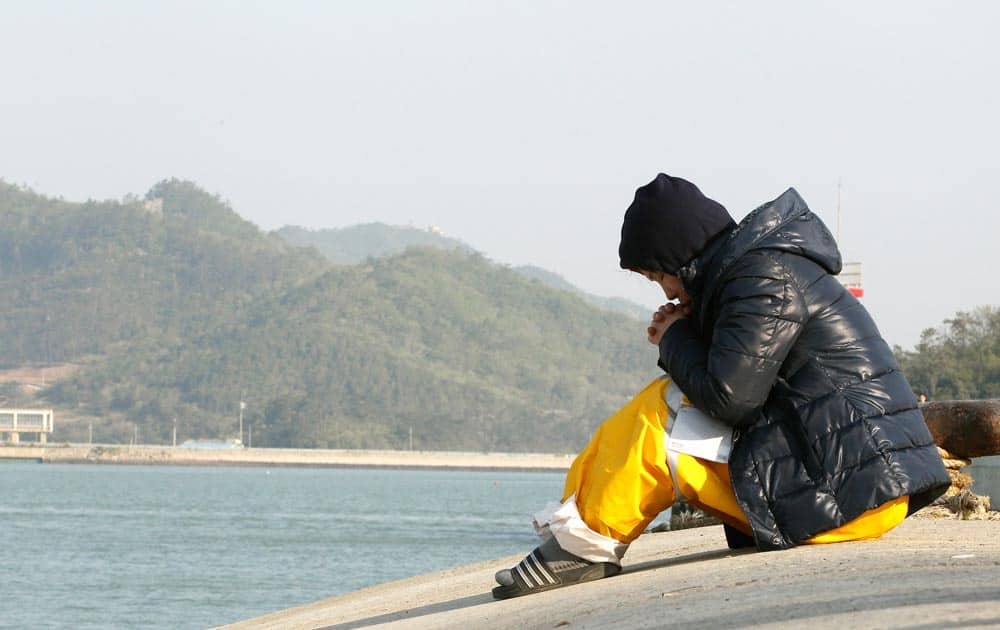 A relative of a passenger aboard the sunken ferry Sewol prays as she waita for her missing loved one at a port in Jindo, South Korea.