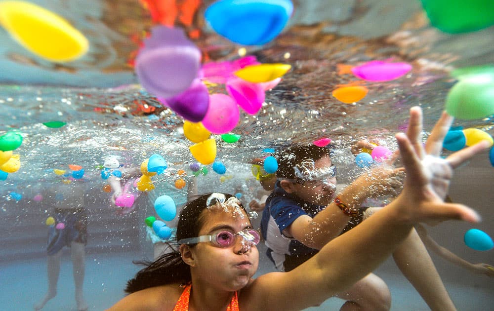 Ten-year olds Kaitlynn Tran of Chicago, and Michael Ramirez of Aurora, Ill., right, gather plastic eggs floating in the Peoria AquaPlex pool during an underwater egg hunt in Peoria, Ill. 