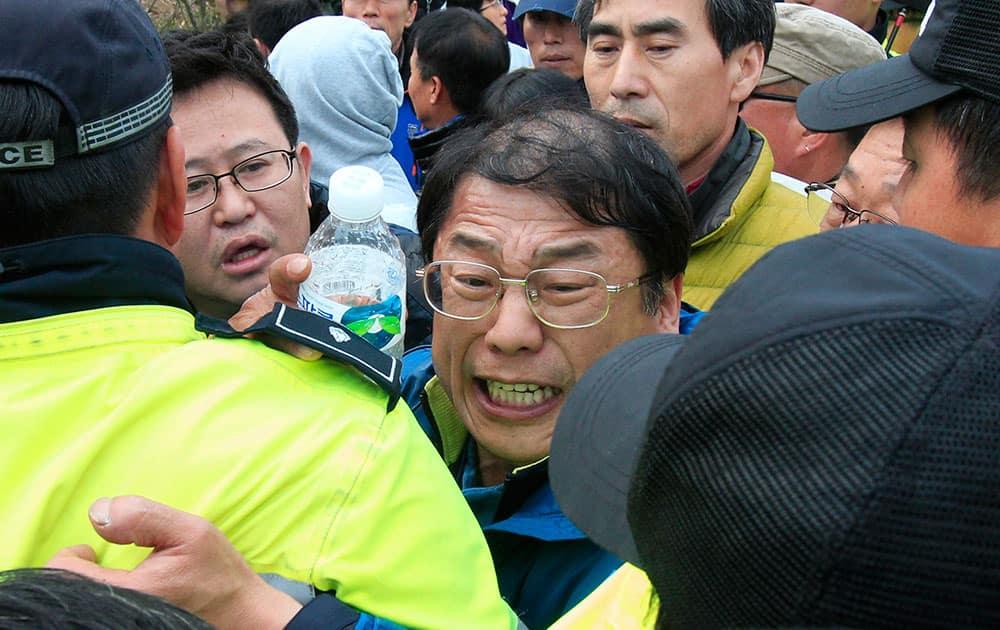 Relatives of missing passengers aboard the sunken ferry Sewol struggle with policemen as they try to march toward the presidential house to protest the government`s rescue operation at a port in Jindo, South Korea.