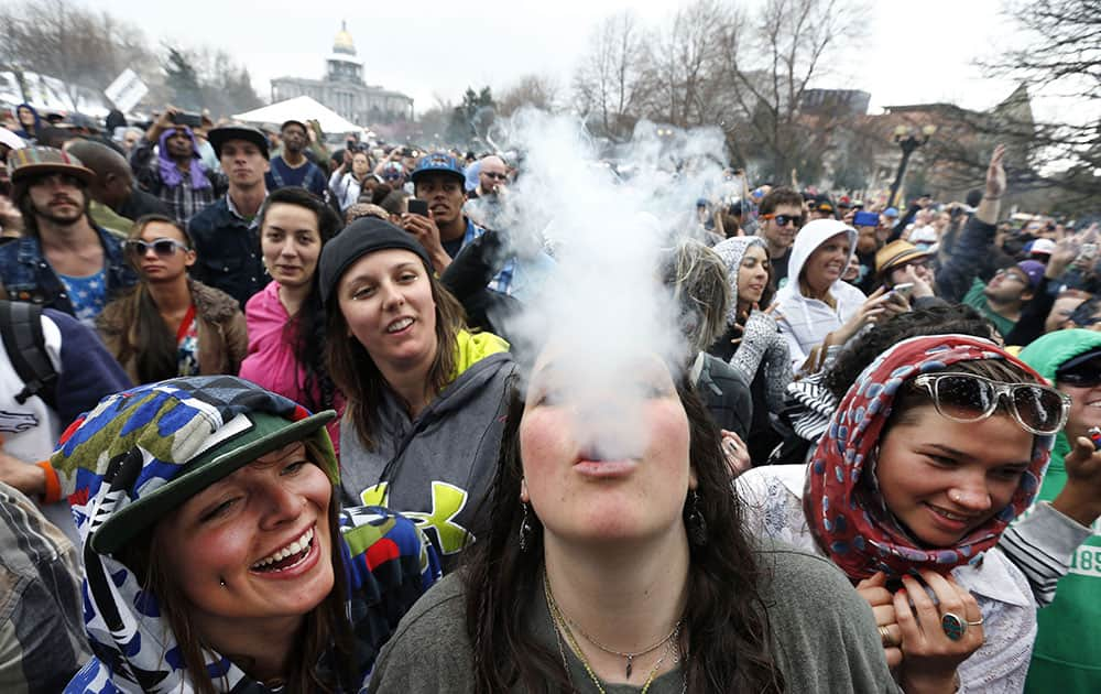 With the Colorado state capitol building visible in the background, partygoers dance and smoke pot on the first of two days at the annual 4/20 marijuana festival in Denver.