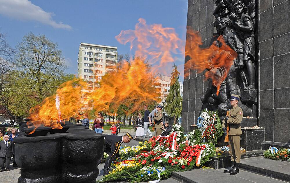 Flames rise from a menorah as a municipal guard lays a wreath during a ceremony marking the 71st anniversary of the beginning of the Warsaw Ghetto Uprising in Warsaw, Poland, in front of the Warsaw Ghetto Heroes Memorial.