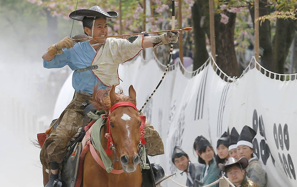 A dressed archer on the horse back prepares to shoot a wooden target in the Asakusa Yabusame horseback archery event at Sumida Park in Tokyo.