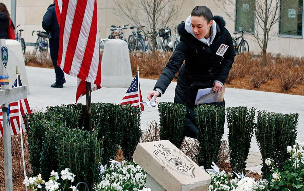 Massachusetts Institute of Technology employee Jennifer Earls places a folded paper crane near a memorial stone after a one-year remembrance ceremony for MIT Officer Sean Collier on campus in Cambridge, Mass.