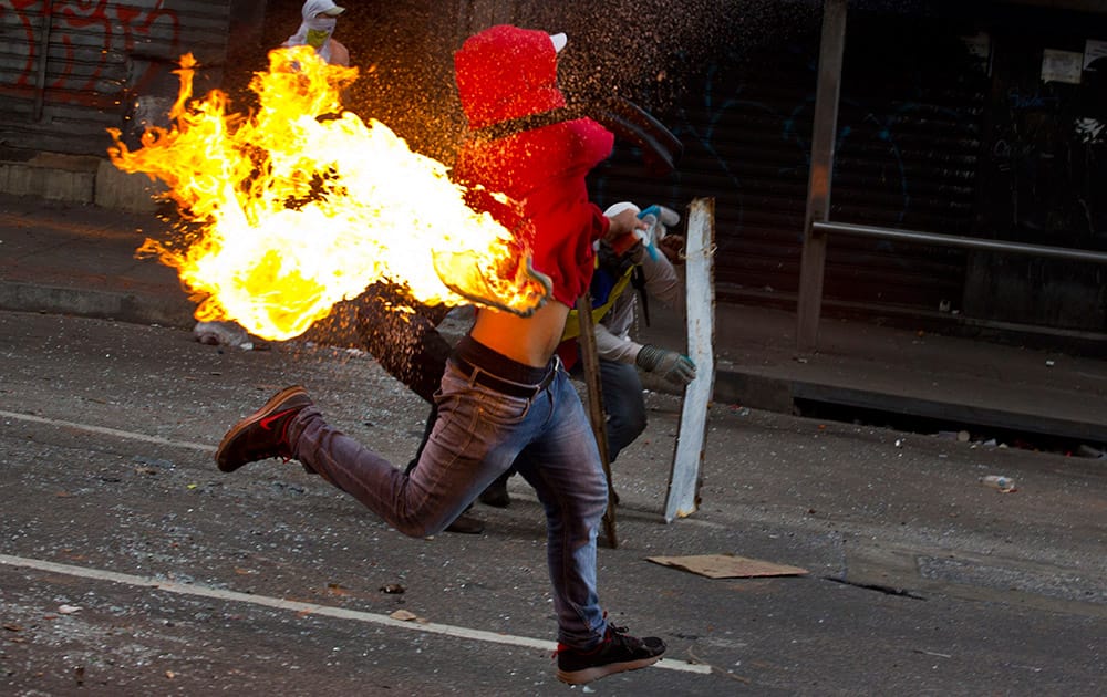 An anti-government protester throws a molotov cocktail at the Bolivarian National Police during clashes in Caracas, Venezuela. Opposition protesters have been demonstrating against high crime, high inflation and shortages of basic goods since mid-February.