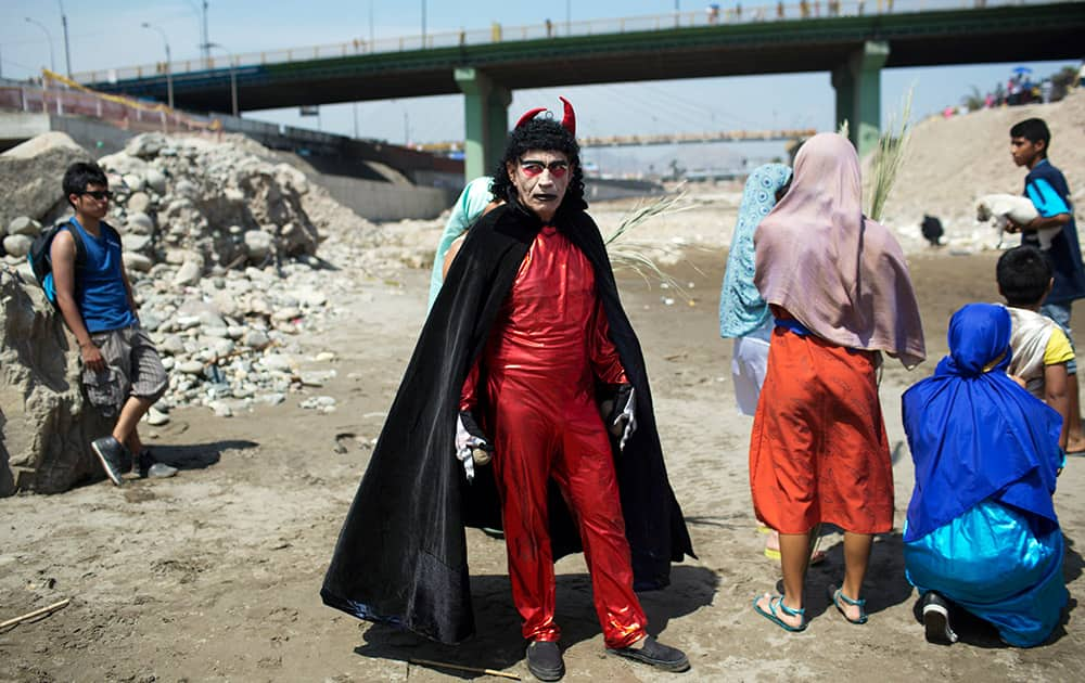 An actor dressed in a devil costume stands on the shores of the Rimac River in Lima, Peru. The actor performed for people after they attended the reenactment of Jesus` baptism in the river as part of during Holy Week celebrations.