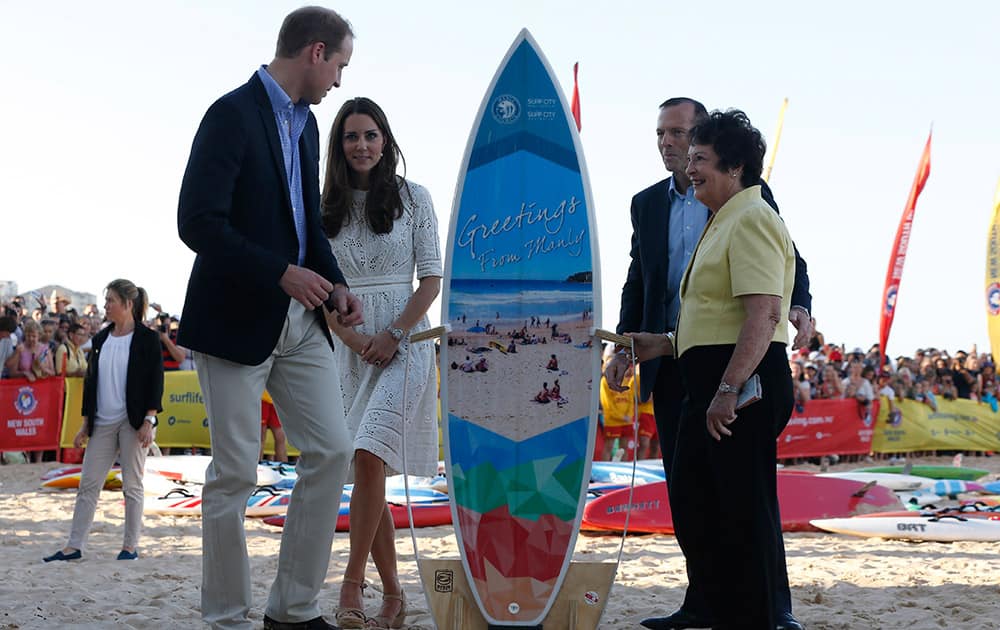 Britain`s Prince William and his wife Kate, the Duchess of Cambridge look at a surfboard presented to them alongside Australian Prime Minister Tony Abbott and Manly`s Mayor Jean Hay during a surf live saving demonstration at Sydney`s Manly Beach.