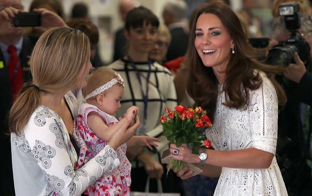 Britain`s Kate, the Duchess of Cambridge, smiles after getting flowers from a baby during a tour of the Sydney Easter Show in Sydney, Australia.