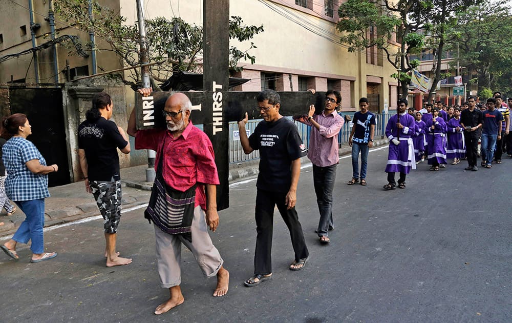 Christian devotees carry a huge wooden cross as they participate in Good Friday procession in Kolkata.