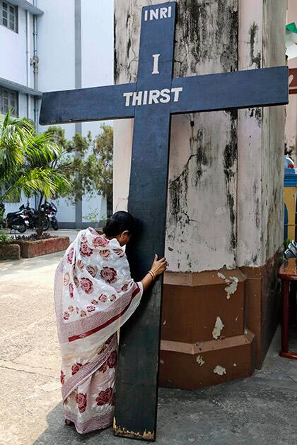 A Christian woman touches a huge cross as she prays on Good Friday in Kolkata.