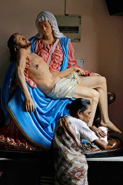 A Catholic woman touches her fractured hand in the belief that it will heal as she stands in front of a portrait of Mother Mary and Jesus Christ on Good Friday in Kolkata.