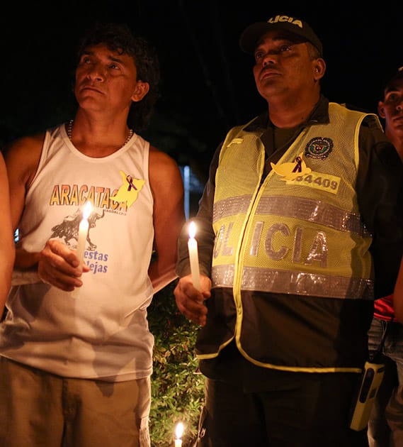 A police officer, right, holds a candle during a vigil in front of the Gabriel Garcia Marquez Museum, at the house were he was born in Aracataca, Colombia.