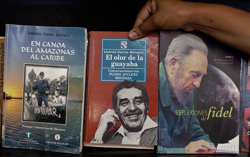 A woman shows a book by Colombian author Gabriel Garcia Marquez for sale next to a book by Fidel Castro at a state-run bookstore in Havana, Cuba.