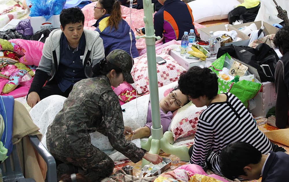 An army doctor attends one of parents whose children were aboard the Sewol ferry and are now missing, on the floor at a gymnasium in Jindo, South Korea.