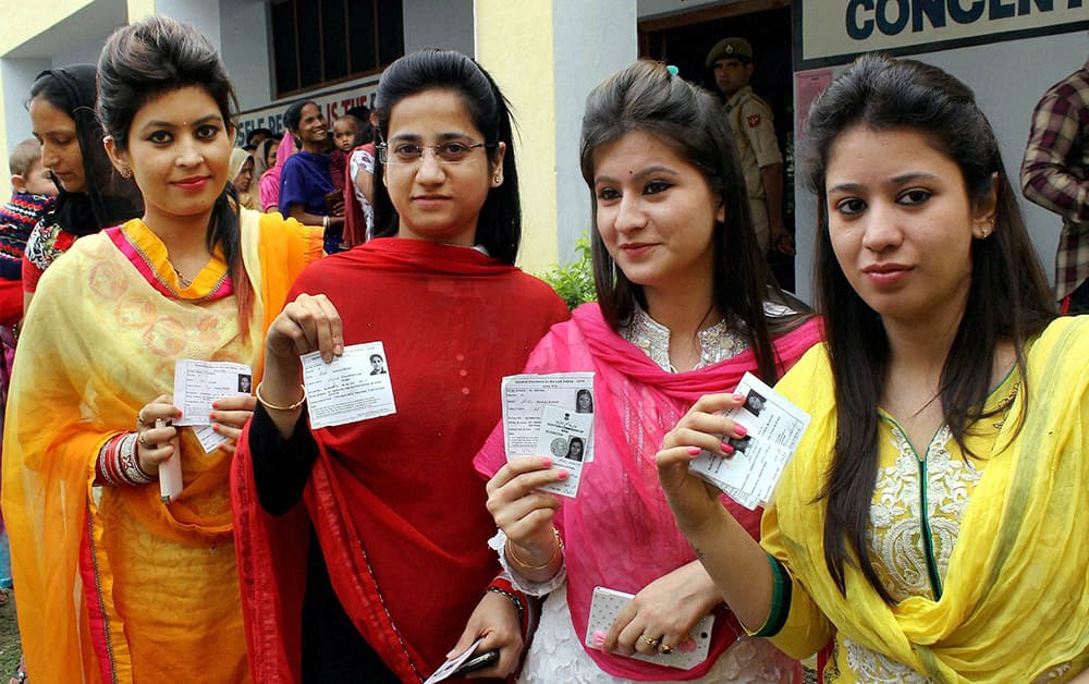 Girls show their voter identity cards as they wait to cast their votes for Lok Sabha elections at a polling booth in Kathua.