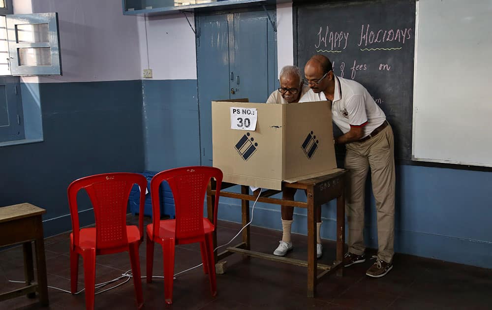 Hari Das helps his father cast his vote at a polling station set up inside a school in Bangalore.