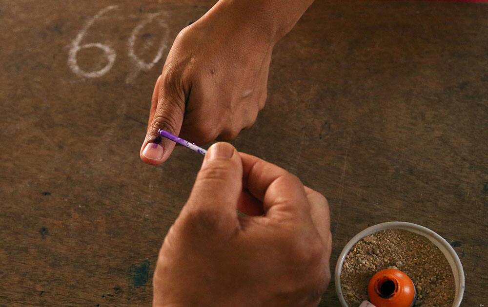 A polling officer marks the finger of a voter with indelible ink at a polling station in Bangalore.