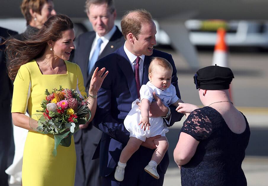 Britain`s Prince William, center, his wife Kate, the Duchess of Cambridge, left, and their son Prince George are presented with flowers by Joscelyn Sweeney upon arrival at Sydney, Australia.