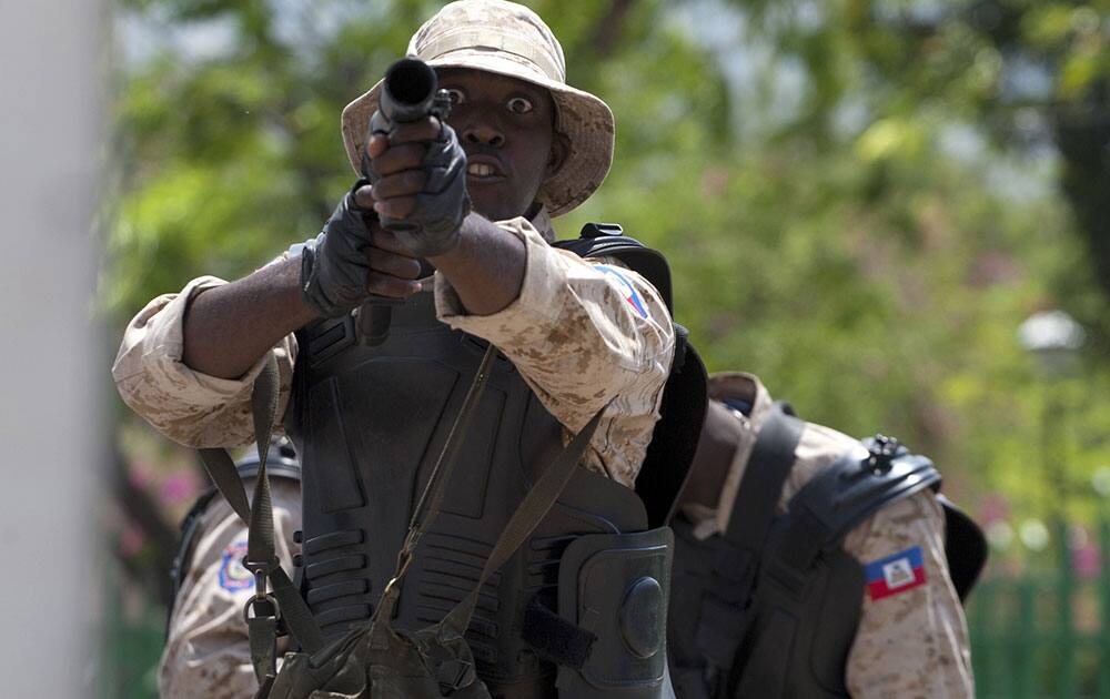 A National Police officer readies to fire tear gas at protestors during an anti-goverment protest in Port-au-Prince, Haiti.