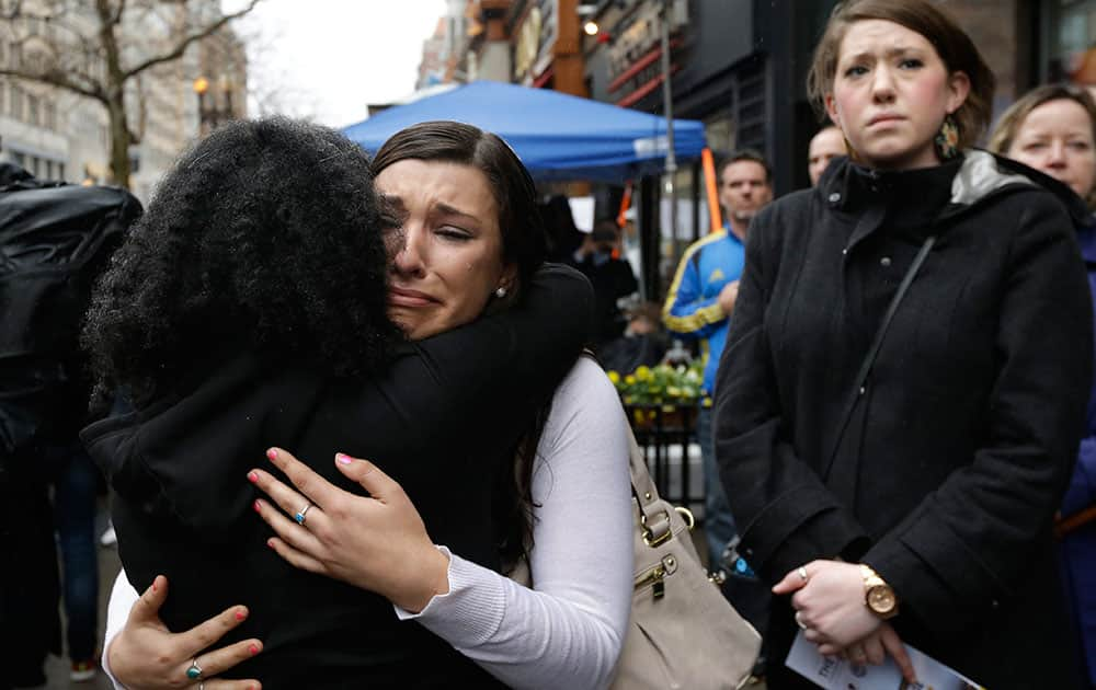 Olivia Savarino, center, hugs Christelle Pierre-Louis, left, as Callie Benjamin, right, looks on near the finish line of the Boston Marathon during ceremonies on Boylston Street, in Boston. Savarino and Benjamin were working at the Forum restaurant when a bomb went off in front of the building on April 15, 2013.