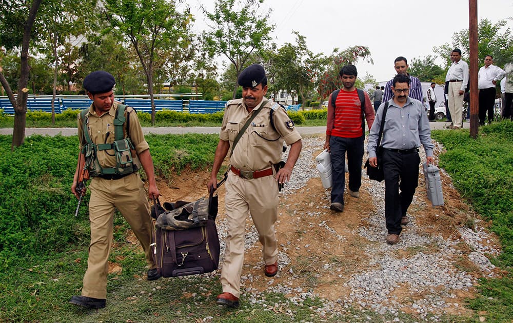 Security personnel return with their luggage as polling officials carry electronic voting machines after collecting them from a distribution center ahead of the fifth phase of Indian parliamentary elections in Udhampur, Jammu.