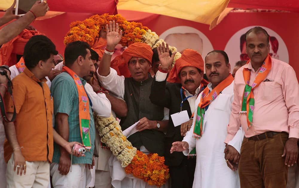 Supporters place a garland on President of Bharatiya Janata Party Rajnath Singh during an election campaign in Udhampur.