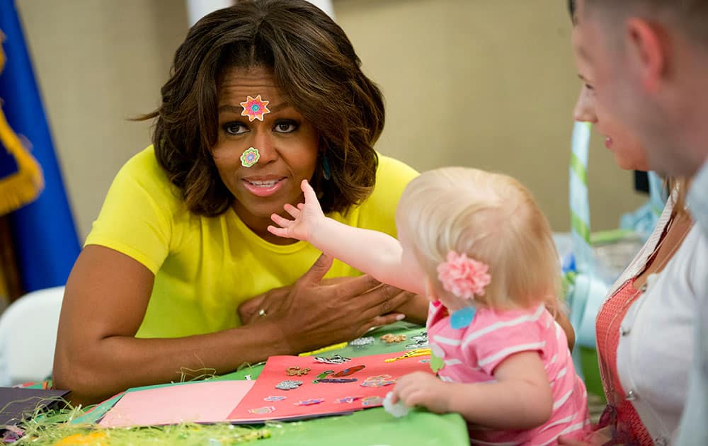 First lady Michelle Obama has stickers placed on her face by 20-month-old Lily Oppelt, as her parents Amy and Sgt. Lucas Oppelt, far right, from Indiana, watch during her visit with Wounded Warriors being cared for at the Fisher House at Walter Reed National Military Medical Center in Bethesda, Md.