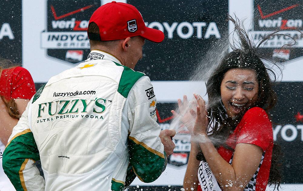 Winner Mike Conway, left, of England sprays Clarissa Burquez, Miss Grand Prix of Long Beach runner-up, with sparkling wine on the podium after the IndyCar Grand Prix of Long Beach auto race in Long Beach, Calif.
