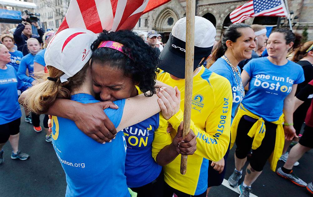 Rosa Evora, center, hugs a fellow participant in a cross country relay that began in March in California and ended at the Boston Marathon finish line in Boston.
