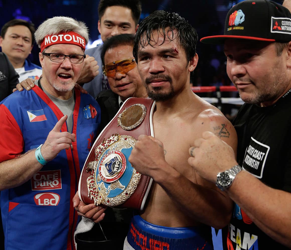 Manny Pacquiao, of the Philippines, center, is joined by trainer Freddie Roach, left, as he poses with the champion`s belt following his unanimous decision against Timothy Bradley in their WBO welterweight title boxing fight in Las Vegas.