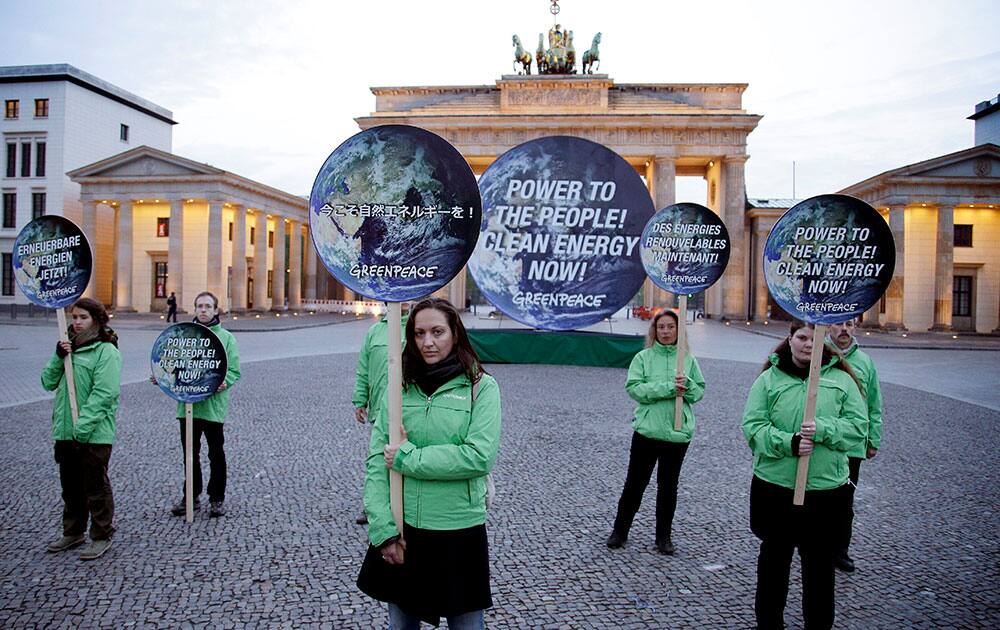 Activists of the international environmentalist organization Greenpeace pose with posters in front of the Brandenburg Gate in Berlin, Germany, to support clean energy.