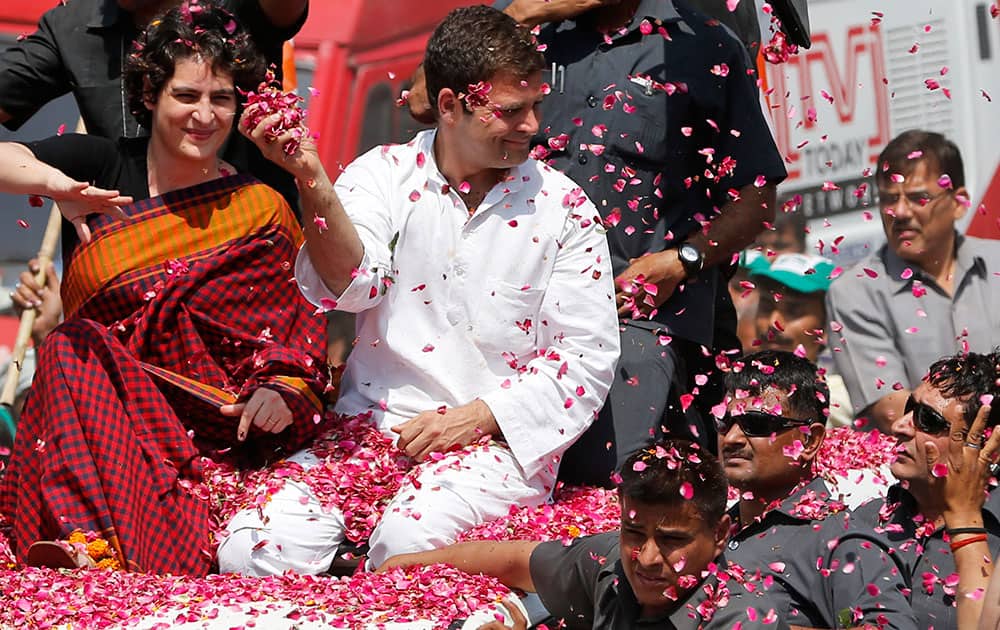 Vice President of India’s ruling Congress party Rahul Gandhi, second right, holds a handful of flower petals to throw back at supporters, with his sister Priyanka Vadra seated by his side as he arrives to file his nomination for the ongoing general elections in Amethi, in the northern Indian state of Uttar Pradesh.