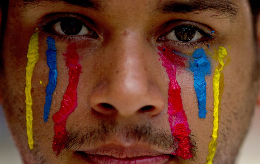 A university student wearing painted tears in the colors of Venezuela`s flag looks into the camera during an anti-government protest in Caracas, Venezuela.
