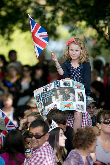 A young girl waves a flag as crowds gather in Cambridge, New Zealand, waiting for the arrival of the Duke and Duchess of Cambridge.