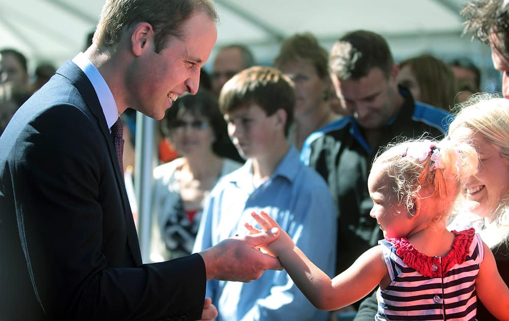 Britain`s Prince William, left, chats with a young girl while visiting aircraft manufacturer Pacific Aerospace near Hamilton, New Zealand.