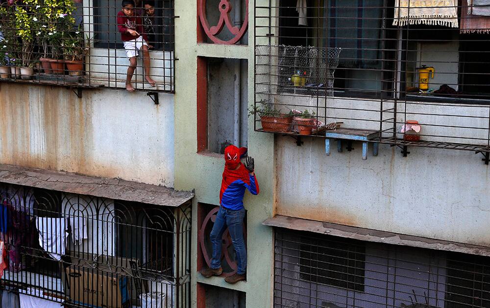 Residents watch as Gaurav Sharma, locally known as Indian Spiderman who is contesting as an independent candidate in the upcoming parliamentary elections climbs a building as part of his campaign in Mumbai.