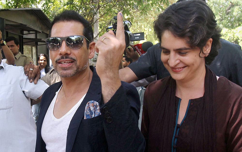 Priyanka Vadra walks beside her husband Robert Vadra who displays the indelible ink on his finger after they cast their votes in New Delhi.