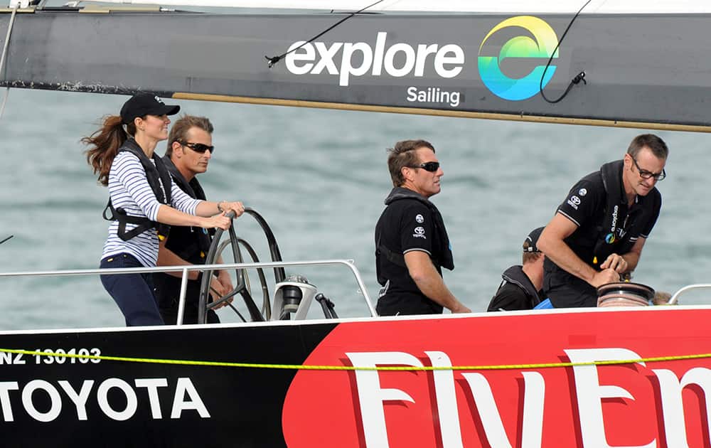 Britain`s Kate, the Duchess of Cambridge stands with New Zealand Americas Cup skipper Dean Barker in a match race against her husband Prince William on the Waitemata Harbour in Auckland, New Zealand.