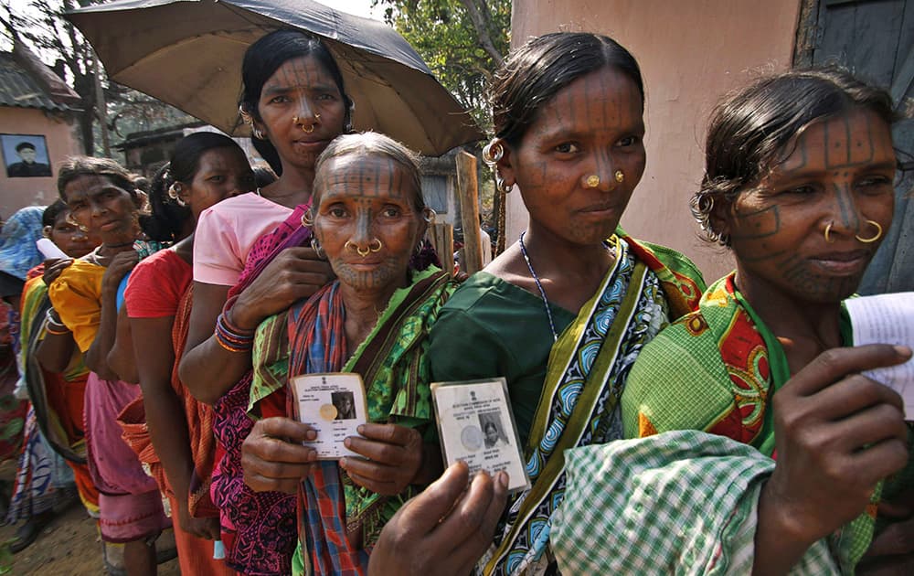 Indigenous women belonging to the Kandha tribe display their voter`s identity cards as they wait to cast their votes outside a polling station during Indian parliamentary elections at Dingesiguda village in Kandhamal district, Odisha.