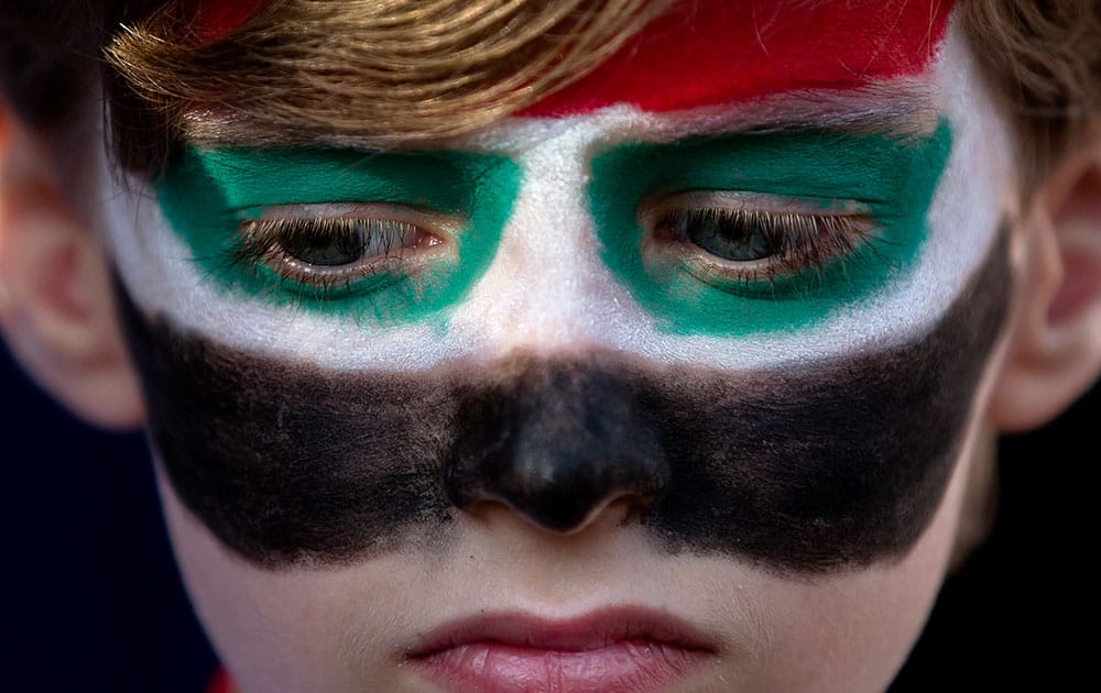 A child of the Syrian community in Romania with his face painted in the colors of Syria`s flag, attends a demonstration in support of Syrian President Bashar Assad`s regime, in Bucharest, Romania.