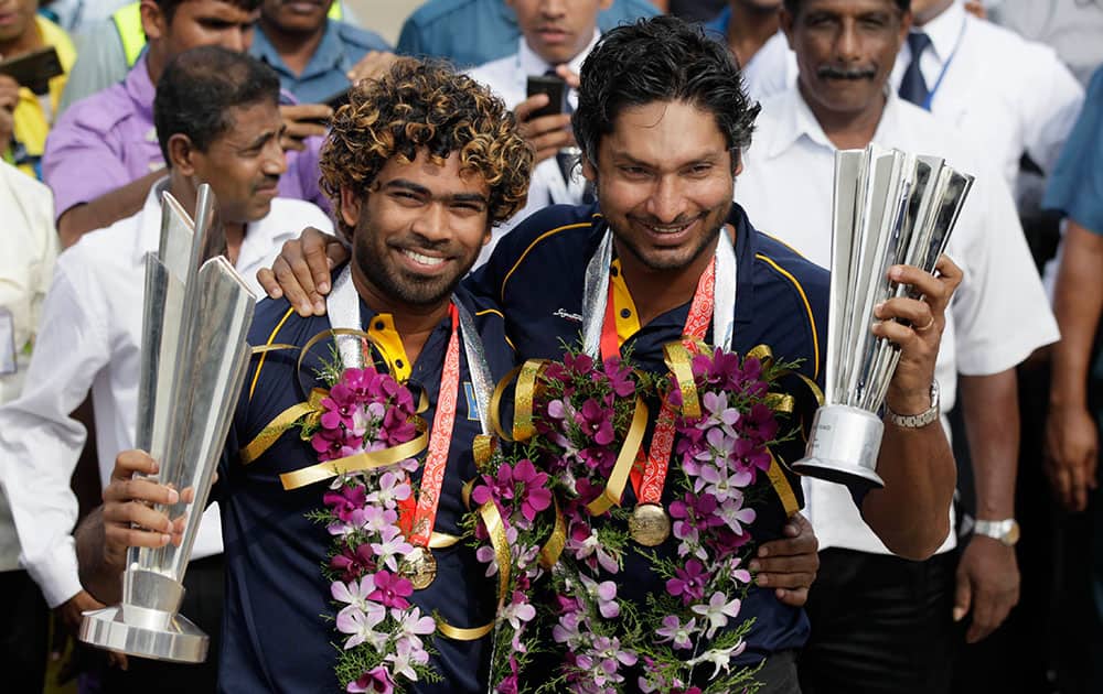 Sri Lanka`s T20 cricket World Cup winning team`s captain Lasith Malinga, left, and teammate Kumar Sangakkara pose with their trophies upon the arrival from Dhaka in Colombo, Sri Lanka.