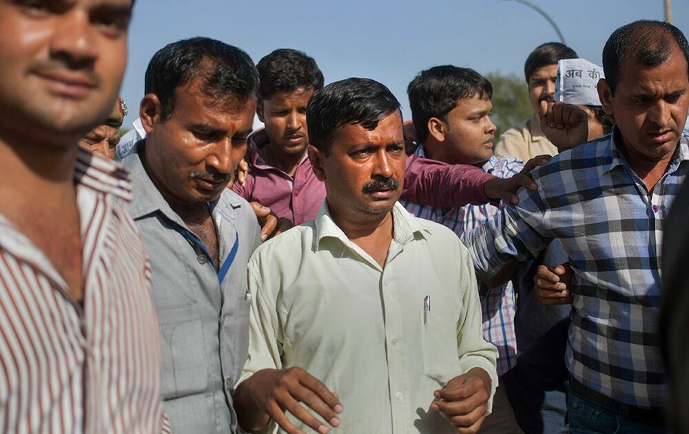 Aam Aadmi Party chief Arvind Kejriwal stands with supporters at Rajghat, the memorial of Mahatma Gandhi after he was slapped by an attacker during his election campaign in New Delhi.