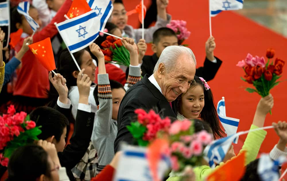 Israeli President Shimon Peres hugs Chinese children during a welcome ceremony held by Chinese president Xi Jinping at the Great Hall of the People in Beijing.