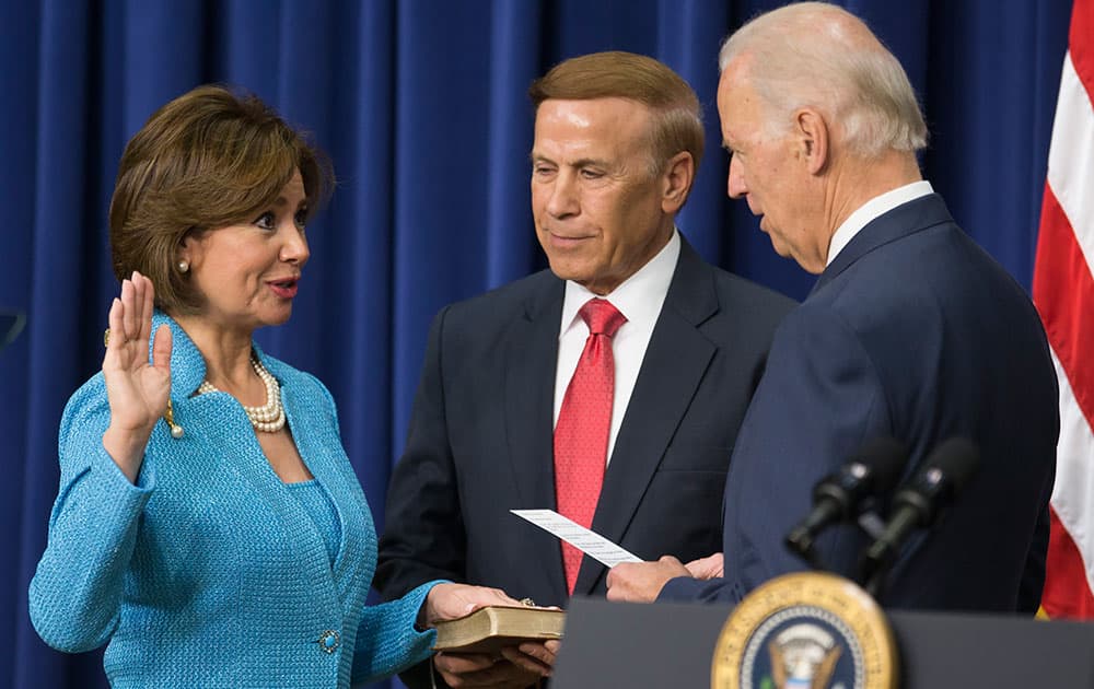 Ray Sweet, center, holds the Bible as his wife Maria Contreras-Sweet, left, takes part in a ceremonial swearing in as administrator of the Small Business Administration with Vice President Joe Biden, in the South Court Auditorium on the White House complex, in Washington.