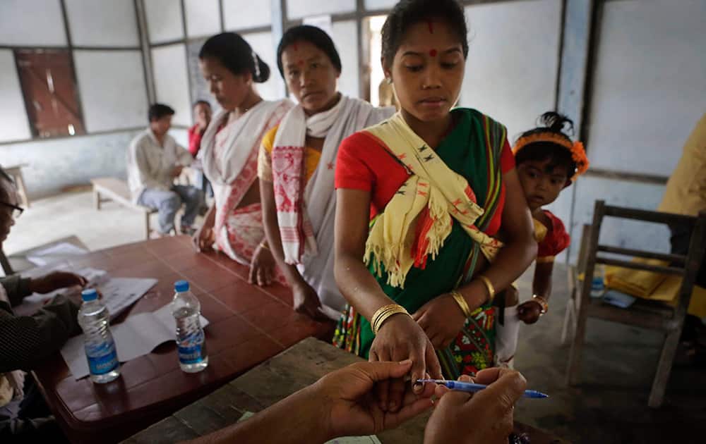 An election officer applies an indelible ink mark on the finger of a Mishing tribal woman voter during the first phase of elections at Misamora Sapori, an island in the River Brahmaputra in the northeastern Assam.