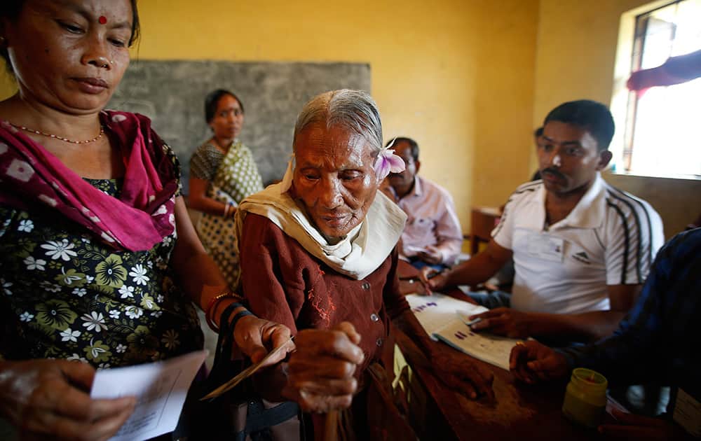 An elderly woman is helped as she prepares to cast her vote during the first phase of elections in Mandai, in the northeastern state of Tripura.