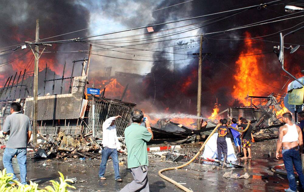 Residents and charity workers try to put out a fire caused by a bomb blast in downtown Yala province, southern Thailand. Suspected Muslim insurgents in southern Thailand launched a wave of attacks Sunday that killed one person and wounded 24 others.